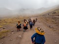 Natives with horses walk down dirt road dressed with colorful traditional clothes, fog