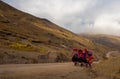 Three indian woman walk up mountain path wearing red and black traditional clothes