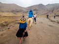 Tourists and locals walk on dirt road towards rainbow mountain