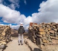 Young man enjoys the view from top of mountain next to stone wall, big white clouds on the sky Royalty Free Stock Photo