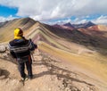 Man in indian clothes enjoys the rainbow mountain view, yellow hat
