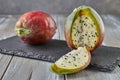 Peruvian apple cactus fruits whole and cut on wooden stand on gray board. Scientific name Cereus repandus