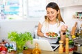 Peruvian housewoman eating salad and watching movie on laptop