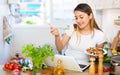 Peruvian housewoman eating salad and watching movie on laptop