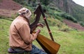 Peruvian man plays the harp on the mountain side