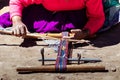 A Peruvian woman makes a multicolored ribbon on a rudimentary loom. Lake Titicaca.