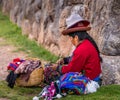 Peruvian woman sewing and making clothing while selling at tourist destination