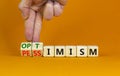 Pessimism or optimism symbol. Businessman turns cubes and changes the word `pessimism` to `optimism`. Beautiful orange table, Royalty Free Stock Photo