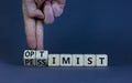 Pessimist or optimist symbol. Businessman turns cubes and changes the word `pessimist` to `optimist`. Beautiful grey table, gr