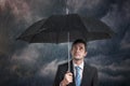 Pessimistic businessman with black umbrella in storm.