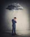 Pessimistic and depressed businessman standing under rain as the negative thoughts stands over his head like a storm cloud. Person Royalty Free Stock Photo