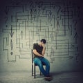 Pessimistic, disappointed man sitting on a chair in a dark room covering face with hand. Desperate guy try to solve a questions