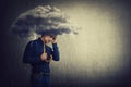 Pessimistic man, standing under rain, suffering anxiety as holding an umbrella thunderstorm cloud over head. Concept of memory Royalty Free Stock Photo