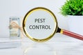 Pest control phrase written through a magnifying glass on a light background near a roll of money and a pot of green grass Royalty Free Stock Photo