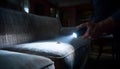 Pest control worker examines a home sofa for cockroaches and other pests using a flashlight. This inspection aims for Royalty Free Stock Photo