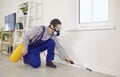 Pest control worker in a mask and overalls spraying insecticide inside the house Royalty Free Stock Photo