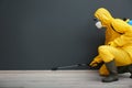 Pest control worker in protective suit spraying pesticide near black wall. Space for text Royalty Free Stock Photo