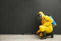 Pest control worker in protective suit spraying pesticide near black wall. Space for text Royalty Free Stock Photo