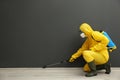 Pest control worker in protective suit spraying pesticide near black wall. Space for text Royalty Free Stock Photo