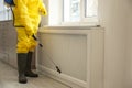 Pest control worker in protective suit spraying pesticide near window, closeup Royalty Free Stock Photo