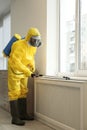 Pest control worker in protective suit spraying pesticide near window Royalty Free Stock Photo