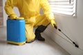 Pest control worker in protective suit spraying pesticide near window, closeup Royalty Free Stock Photo