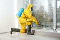 Pest control worker in protective suit spraying pesticide near window Royalty Free Stock Photo