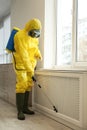 Pest control worker in protective suit spraying pesticide near window Royalty Free Stock Photo