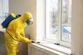 Pest control worker in protective suit spraying pesticide near window Royalty Free Stock Photo