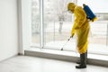 Pest control worker in protective suit spraying pesticide near window Royalty Free Stock Photo