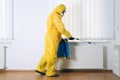 Pest control worker in protective suit spraying pesticide Royalty Free Stock Photo