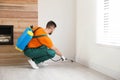 Pest control worker spraying insecticide on baseboard at home. Space for text Royalty Free Stock Photo