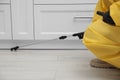 Pest control worker spraying pesticide around furniture indoors, closeup Royalty Free Stock Photo