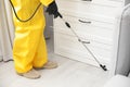 Pest control worker spraying pesticide around furniture indoors Royalty Free Stock Photo