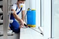 Pest control worker spraying pesticide near window Royalty Free Stock Photo