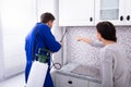 Woman And Worker Spraying Pesticide In Kitchen Royalty Free Stock Photo