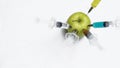 Pesticides, nitrates, gmo and other chemicals are injected into green apple with syringes. Top view.