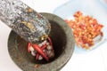 Pestle is above mortar with chilli and garlic inside Royalty Free Stock Photo