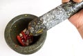 Pestle in woman hand above the mortar with chilli and garlic ins Royalty Free Stock Photo