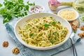 Pesto pasta, bavette with walnuts, parsley, garlic, nuts, olive oil. Side view, close-up, blue background.