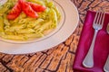 Pesto penne pasta with fresh tomatoes and iced tea on a tree stump background. Royalty Free Stock Photo