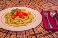 Pesto penne pasta with fresh tomatoes and iced tea on a tree stump background. Royalty Free Stock Photo