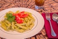 Pesto penne pasta with fresh tomatoes and iced tea on a tree stump background. Royalty Free Stock Photo