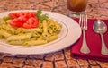 Pesto penne pasta with fresh tomatoes and iced tea on a tree stump background. Royalty Free Stock Photo