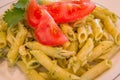 Pesto penne pasta with fresh tomatoes and iced tea on a tree stump background. Royalty Free Stock Photo