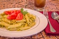 Pesto penne pasta with fresh tomatoes and iced tea on a tree stump background. Royalty Free Stock Photo