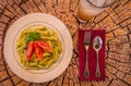 Pesto penne pasta with fresh tomatoes and iced tea on a tree stump background. Royalty Free Stock Photo