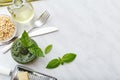 Pesto sauce with cutlery and ingredients: pine nuts, basil, olive oil, parmesan over white marble background. Top view, flat lay Royalty Free Stock Photo