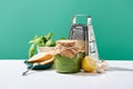 Pesto sauce in jar near ingredients, baguette and grater on white table isolated on green Royalty Free Stock Photo