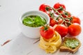 Pesto sauce pasta and tomatoes, white wood background Royalty Free Stock Photo